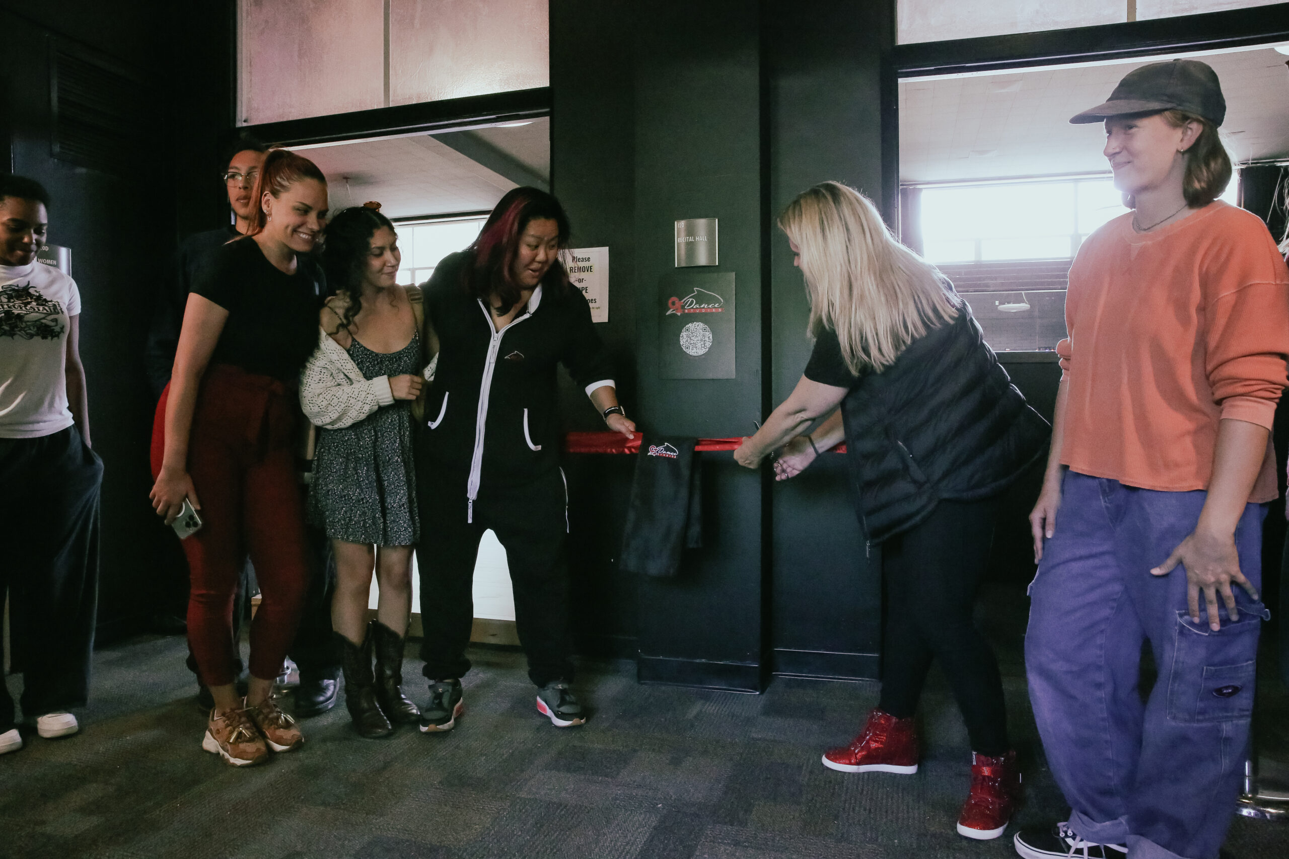 People cutting red ribbon into new dance studio